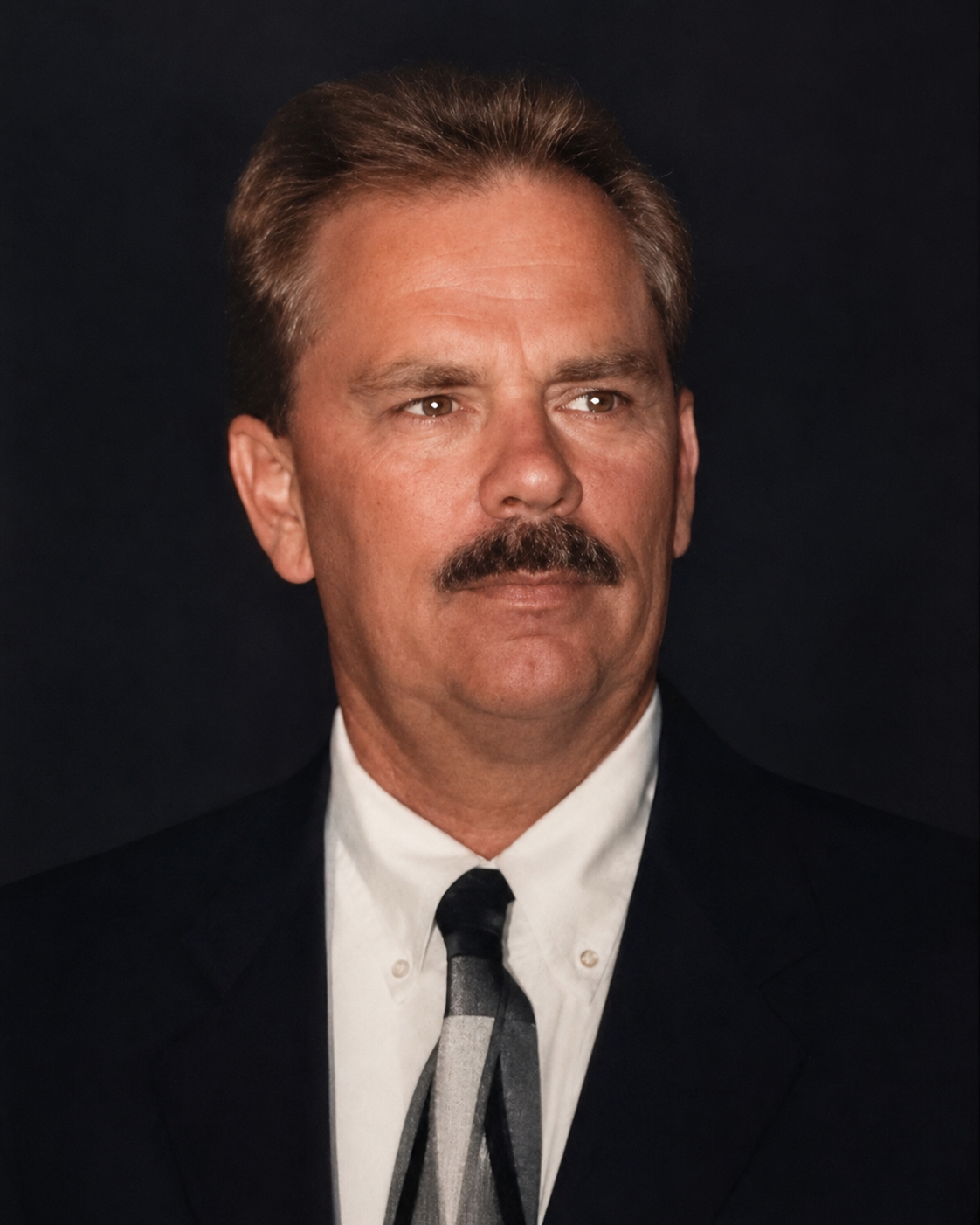 Formal studio portrait of Kim Jeffrey Brown in a dark suit and tie